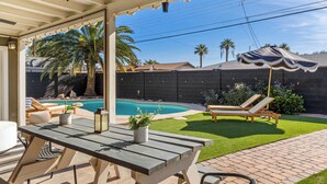 Eine überdachte Terrasse mit Pool, Liegestühlen und einem Tisch mit Topfpflanzen.