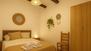 A bedroom with a bed, bedside tables, a chair, a wardrobe, and wall decorations. - Country house in the Sierra Nevada- Almería. Nature, hiking and relaxation (Abrucena)