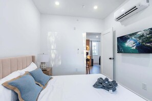 A bedroom with a bed, a TV on the wall, and an air conditioning unit. - Old City - Luxury Waterview Penthouse The Heritage (Philadelphia)