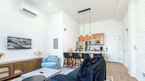 A modern living room with a sofa, coffee table, and a kitchen area with bar stools. - Old City - Luxury Waterview The Heritage (Philadelphia)