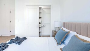 A hotel room with a bed, a wardrobe, and a nightstand with a lamp. - Old City - Luxury Waterview The Heritage (Philadelphia)