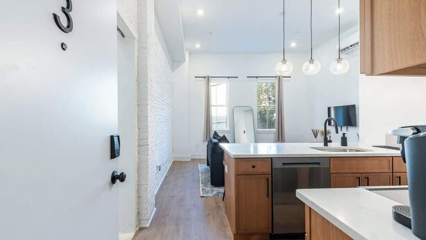 A modern kitchen with wooden cabinets, a stainless steel dishwasher, and pendant lighting. - Old City - Luxury Waterview The Heritage (Philadelphia)