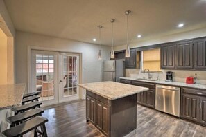 A kitchen with a central island, dark wooden cabinets, stainless steel appliances, and pendant lighting. - Tulane Modern Richardson Retreat w/ Pool & Indoor Hot Tub! (Richardson)