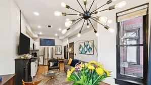 A modern living room with a dining area, a kitchen, and a large window. - Spacious, Historic 4Br Logan Circle Townhome (Washington D.C.)