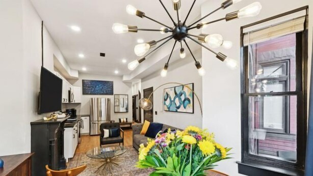 A modern living room with a dining area, a kitchen, and a large window. - Spacious, Historic 4Br Logan Circle Townhome (Washington D.C.)