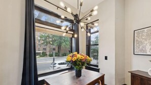 A dining area with a wooden table, chairs, a vase of flowers, and a modern chandelier. - Spacious, Historic 4Br Logan Circle Townhome (Washington D.C.)