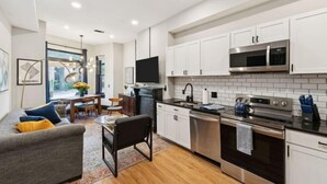 A modern kitchen with white cabinets, stainless steel appliances, and a dining area with a sofa and table. - Spacious, Historic 4Br Logan Circle Townhome (Washington D.C.)