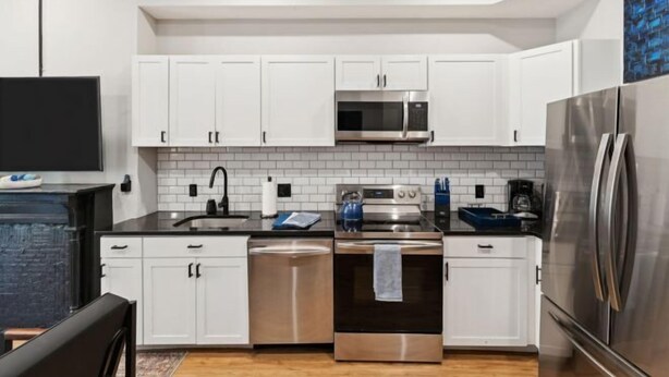 A modern kitchen with white cabinets, stainless steel appliances, and a black countertop. - Spacious, Historic 4Br Logan Circle Townhome (Washington D.C.)