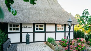 A traditional thatched-roof building with a sign reading 'Ankeplatz' and a bench outside.