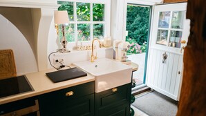 A kitchen with a white countertop, a sink, a coffee maker, and a window with a view of greenery.
