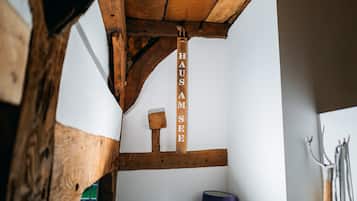 Un interior rústico de madera con vigas a la vista, un letrero de madera que dice 'HAUS AM SEE' y una lámpara.