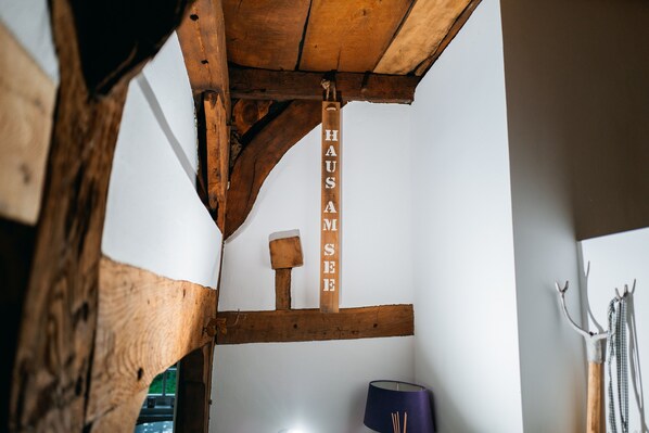 Un interior rústico de madera con vigas a la vista, un letrero de madera que dice 'HAUS AM SEE' y una lámpara.