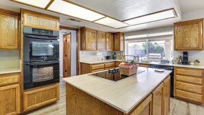 A modern kitchen with wooden cabinets, a built-in oven, a central island, and a large window providing natural light. - Private Hot Tub & Huge Yard: Phoenix Family Home (Phoenix)