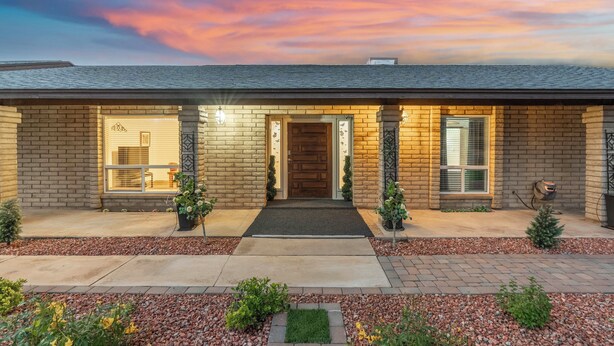 A two-story brick house with a front porch, a garage, and a well-maintained garden. - Private Hot Tub & Huge Yard: Phoenix Family Home (Phoenix)
