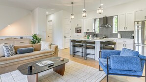 A modern kitchen with white cabinets, a stainless steel refrigerator, and a central island with bar stools. - Sleek, Mod, Luxe: Soccer Fan Home Base in Houston (Houston)