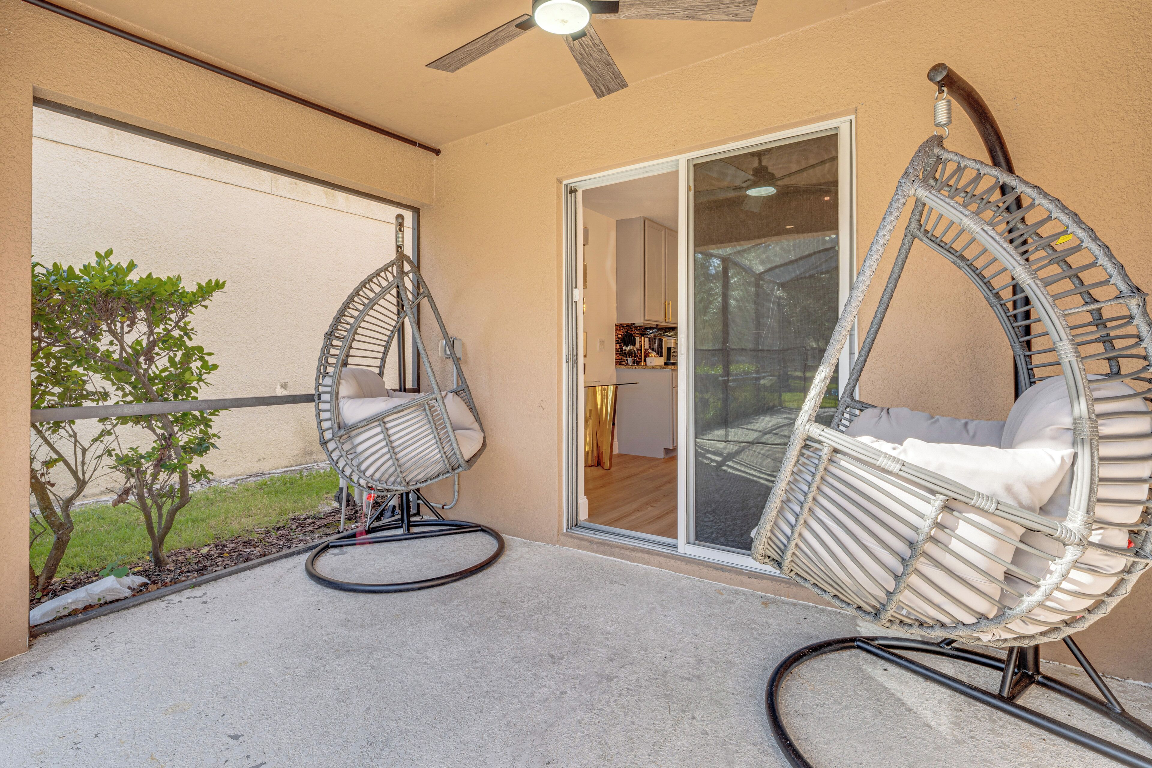Une terrasse avec deux fauteuils à bascule en osier et un ventilateur de plafond.