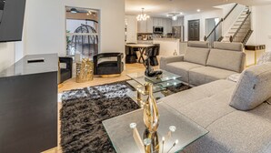 Ein modernes Wohnzimmer mit einem Glastisch, einer Couch und einem Essbereich mit Stühlen.