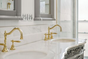 Une salle de bain avec un comptoir en marbre, des robinets dorés et un grand miroir.