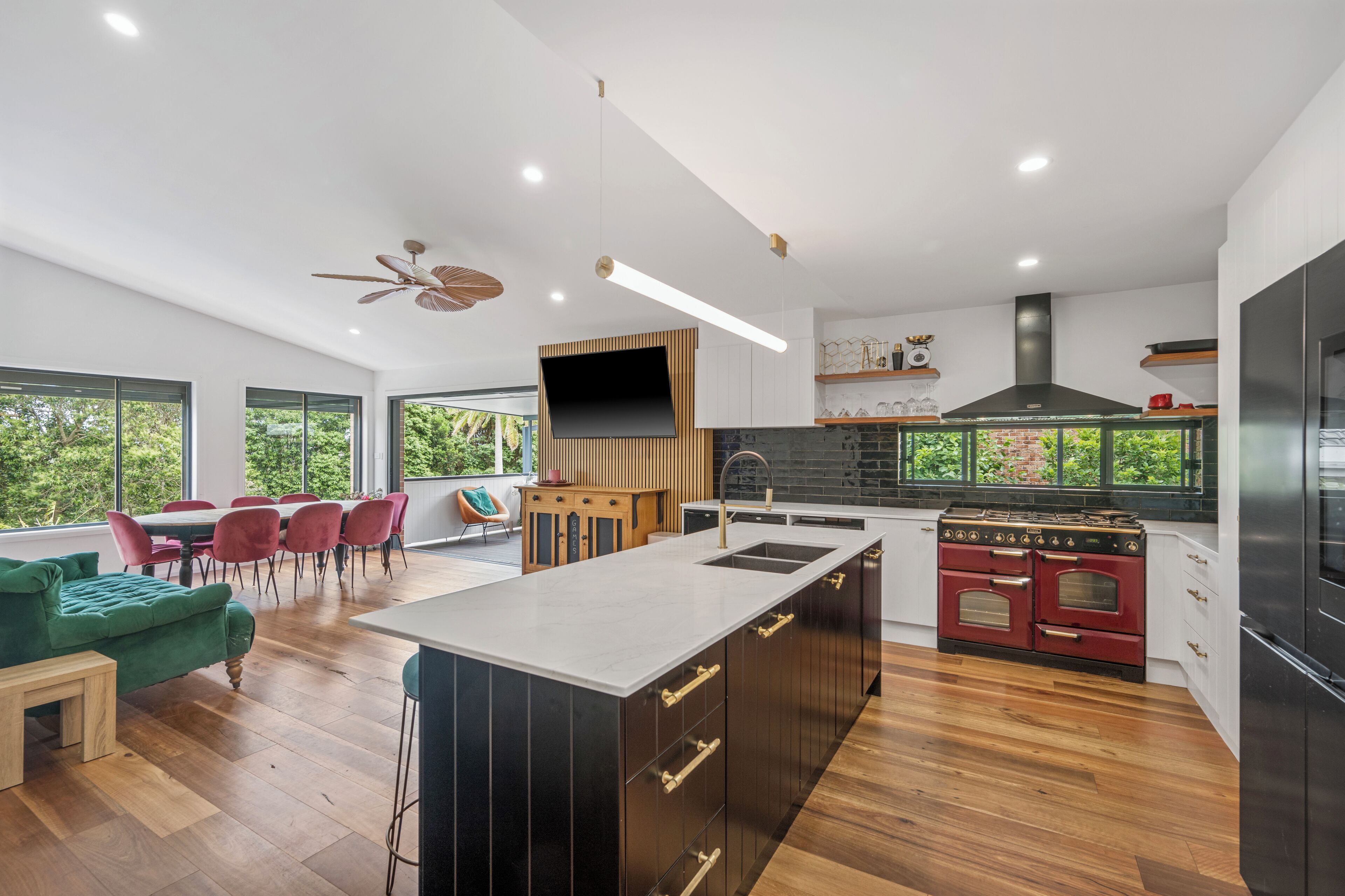 A modern kitchen with a central island, wooden cabinets, and a vintage stove.