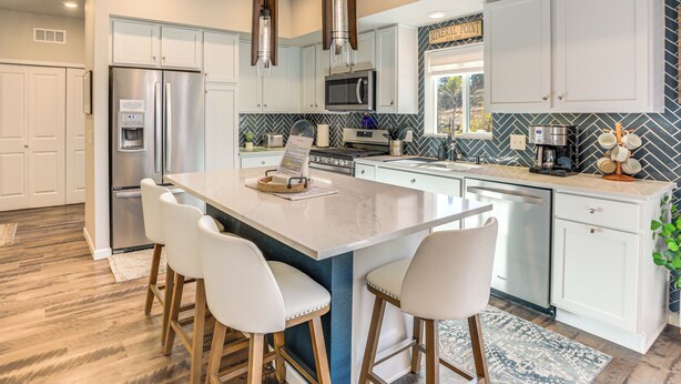 A modern kitchen with white cabinets, stainless steel appliances, and a central island with bar stools. - Walk to Light Rail! Townhome 9 Mi to Dtwn Denver (Lakewood)