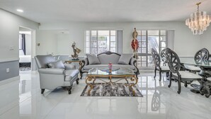 Een ruime woonkamer met een moderne bank, een glazen bijzettafeltje en een kroonluchter.