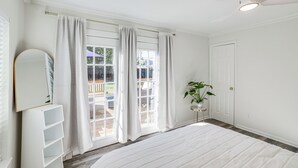Ein heller, weißer Raum mit einem großen Fenster, einem Deckenventilator und einer Topfpflanze.