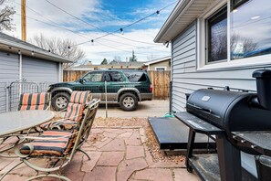 A patio with a grill, a table with chairs, and a parked SUV. - Walk to Old Town Lafayette! Cozy Couples Escape (Lafayette)