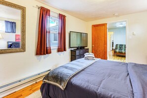 A bedroom with a bed, a television, a mirror, and a door leading to another room. - Walk to Old Town Lafayette! Cozy Couples Escape (Lafayette)