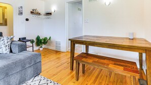 A modern living room with a wooden dining table, a grey sofa, and a small side table with a plant. - Walk to Old Town Lafayette! Cozy Couples Escape (Lafayette)