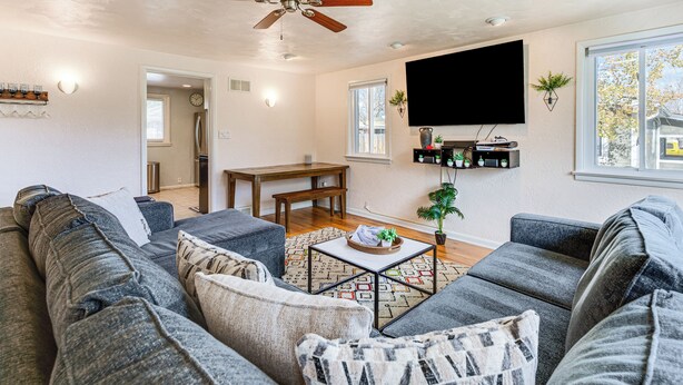 A modern living room with a large gray sectional sofa, a wooden coffee table, and a flat-screen TV mounted on the wall. - Walk to Old Town Lafayette! Cozy Couples Escape (Lafayette)