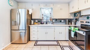 A modern kitchen with white cabinets, stainless steel appliances, and a tiled backsplash. - Walk to Old Town Lafayette! Cozy Couples Escape (Lafayette)
