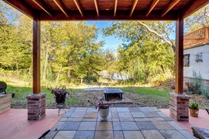 An outdoor patio with a brick fireplace, potted plants, and a view of a wooded area. - Lakefront Getaway w/ Hot Tub & Yard in Okc! (Oklahoma City)