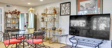 A dining area with a round table and chairs, a TV, and decorative shelves.