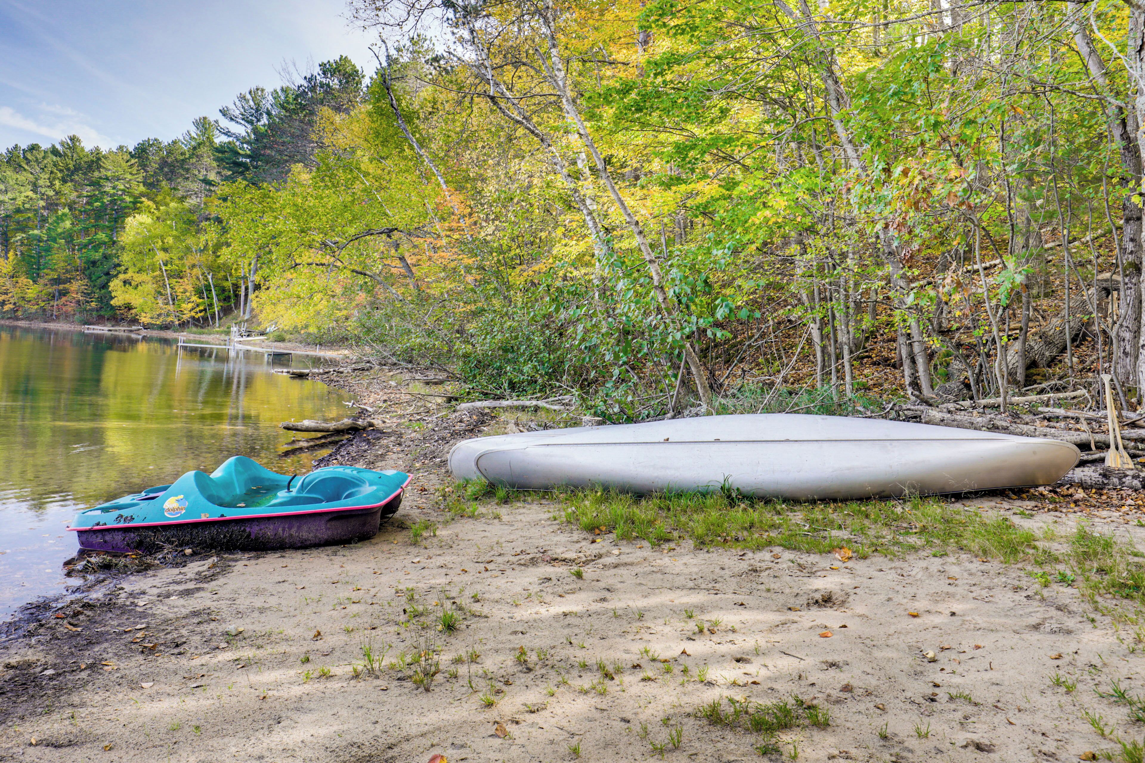 Paesaggio lacustre con un kayak e una canoa sulla riva.