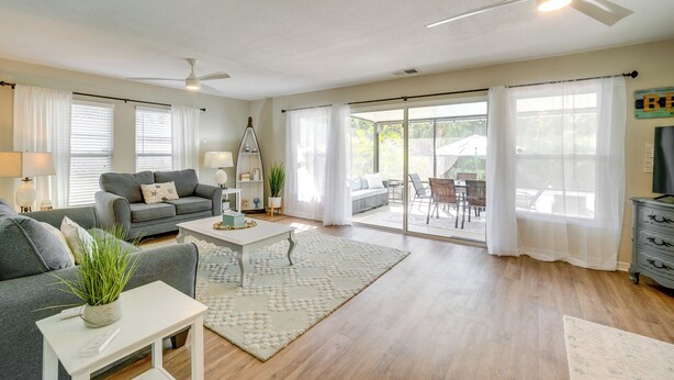 A spacious living room with a grey sofa, white coffee table, and a ceiling fan. - Walk to the Bay: Pet-friendly Oasis in Sarasota! (Sarasota)