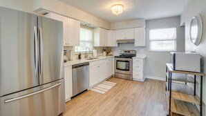 A modern kitchen with stainless steel appliances, white cabinetry, and a wooden floor. - Walk to the Bay: Pet-friendly Oasis in Sarasota! (Sarasota)