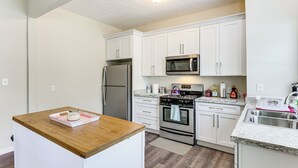 A modern kitchen with white cabinets, stainless steel appliances, and a wooden countertop. - 'doris & Susan's Place' - Historic Tuskegee Home (Tuskegee)