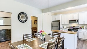 A modern kitchen with white cabinets, a stainless steel refrigerator, and a microwave. - 'doris & Susan's Place' - Historic Tuskegee Home (Tuskegee)