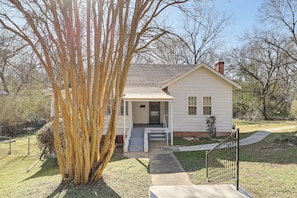A small, single-story house with a front porch, a chimney, and a front yard.