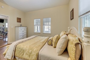 A bedroom with a bed, a dresser, and two windows.