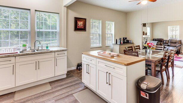 A spacious kitchen with white cabinets, a wooden countertop, and a ceiling fan. - 'doris & Susan's Place' - Historic Tuskegee Home (Tuskegee)