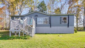 A single-story cabin with a porch and a small staircase, surrounded by a grassy yard and trees. - Relax Fireside! Retreat Near Chickamauga Lake (Decatur)