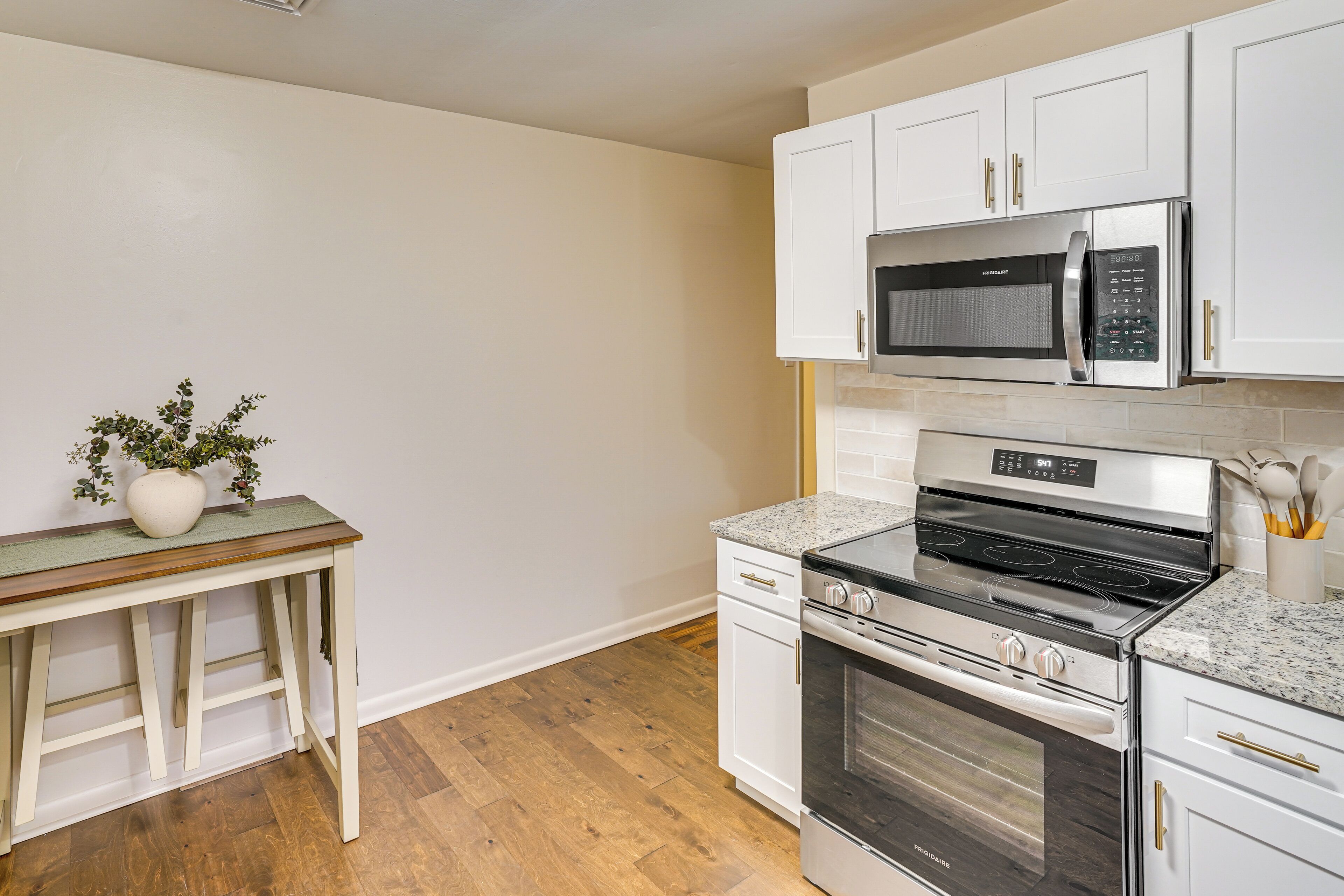 A kitchen with white cabinets, a stainless steel microwave, and a built-in oven.