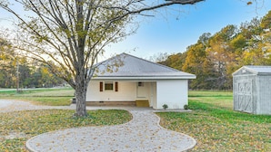 A small, single-story house with a front porch and a gravel driveway.
