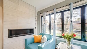A living room with a blue sofa, a fireplace, and a view of the outside through large windows. - Pet Friendly! Near Casinos & Lake Michigan Beaches (Hammond)