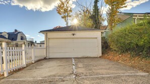 A garage with a white door, surrounded by a white picket fence, and a driveway leading to it. - Easy Commute to Newark & Nyc! Extended Stay Unit (Irvington)