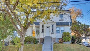 A two-story house with a front porch, a small front yard, and a visible staircase leading to the entrance. - Easy Commute to Newark & Nyc! Extended Stay Unit (Irvington)
