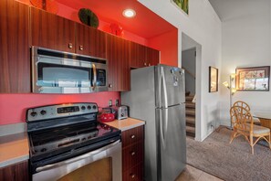 Une cuisine moderne dotée d’appareils électroménagers en acier inoxydable, de meubles en bois et d’un mur d’accent rouge.