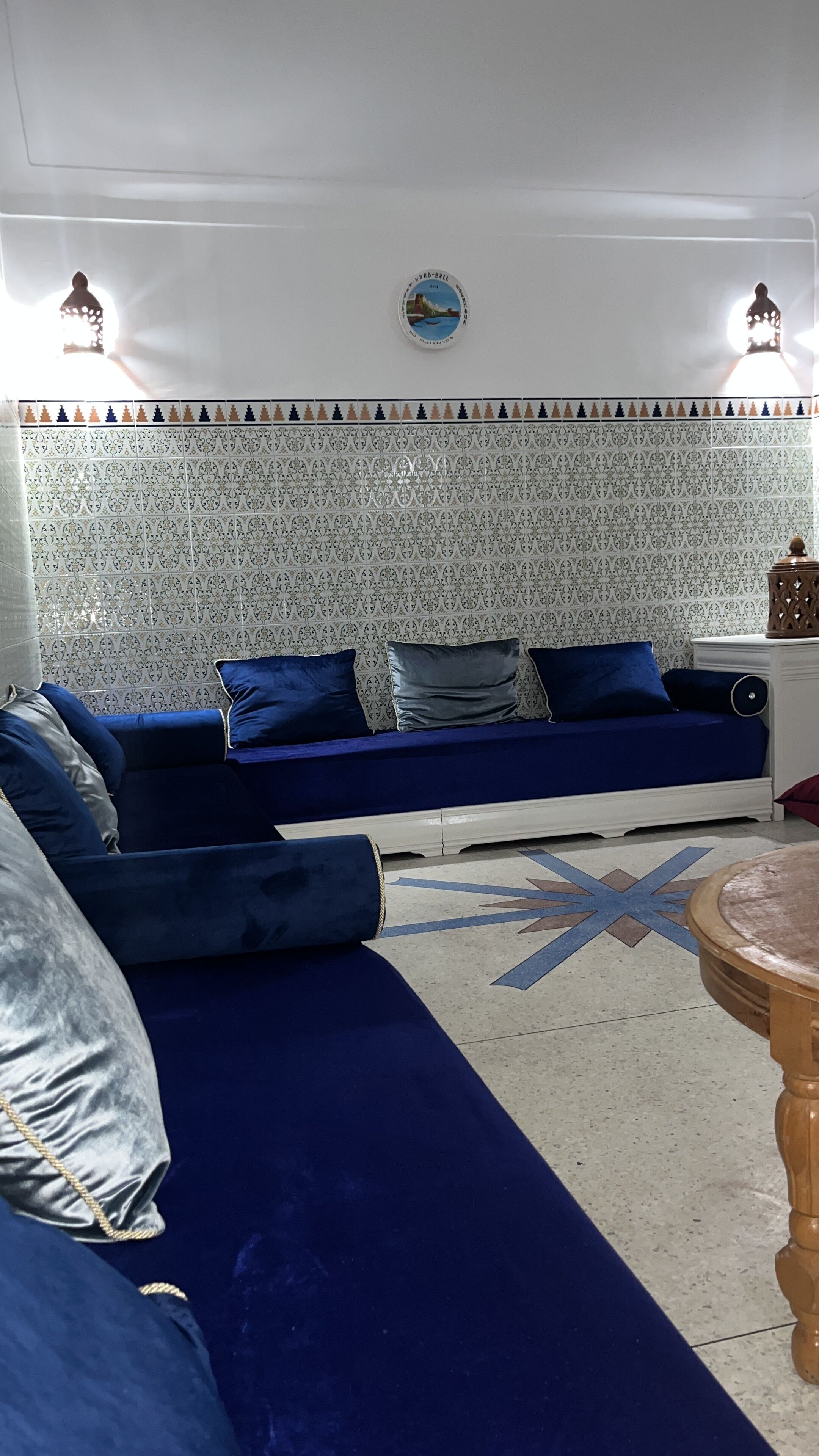 A living room with a blue sofa, patterned wallpaper, and a star-shaped rug.