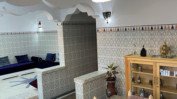 Une pièce avec un mur orné de motifs, un canapé, une table à manger et un lustre.